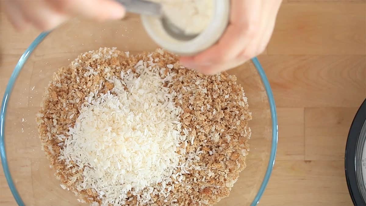 a mixing bowl with breadcrumbs and shredded coconut in it