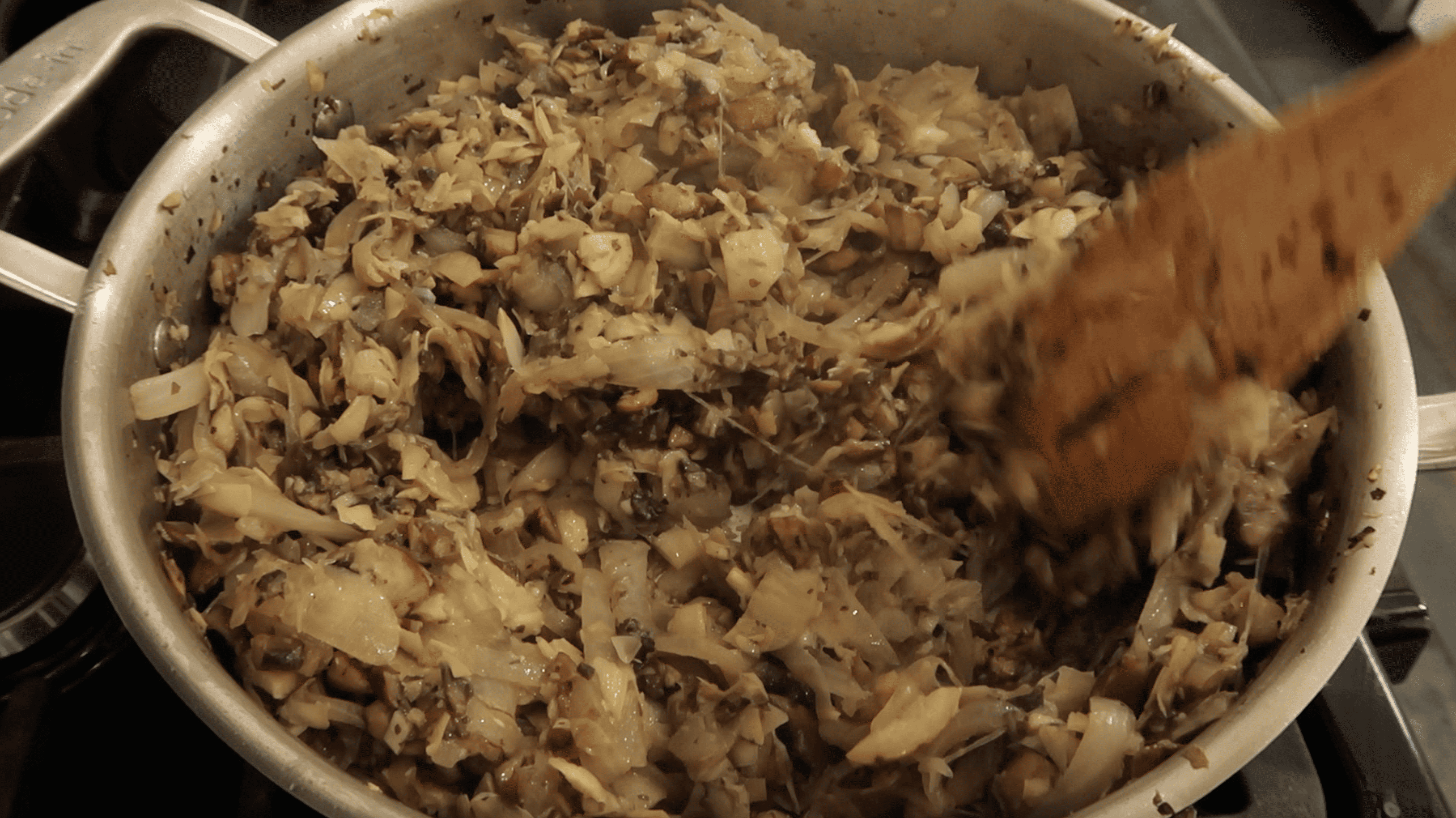 a pan with mushrooms, onions, and artichokes cooked down