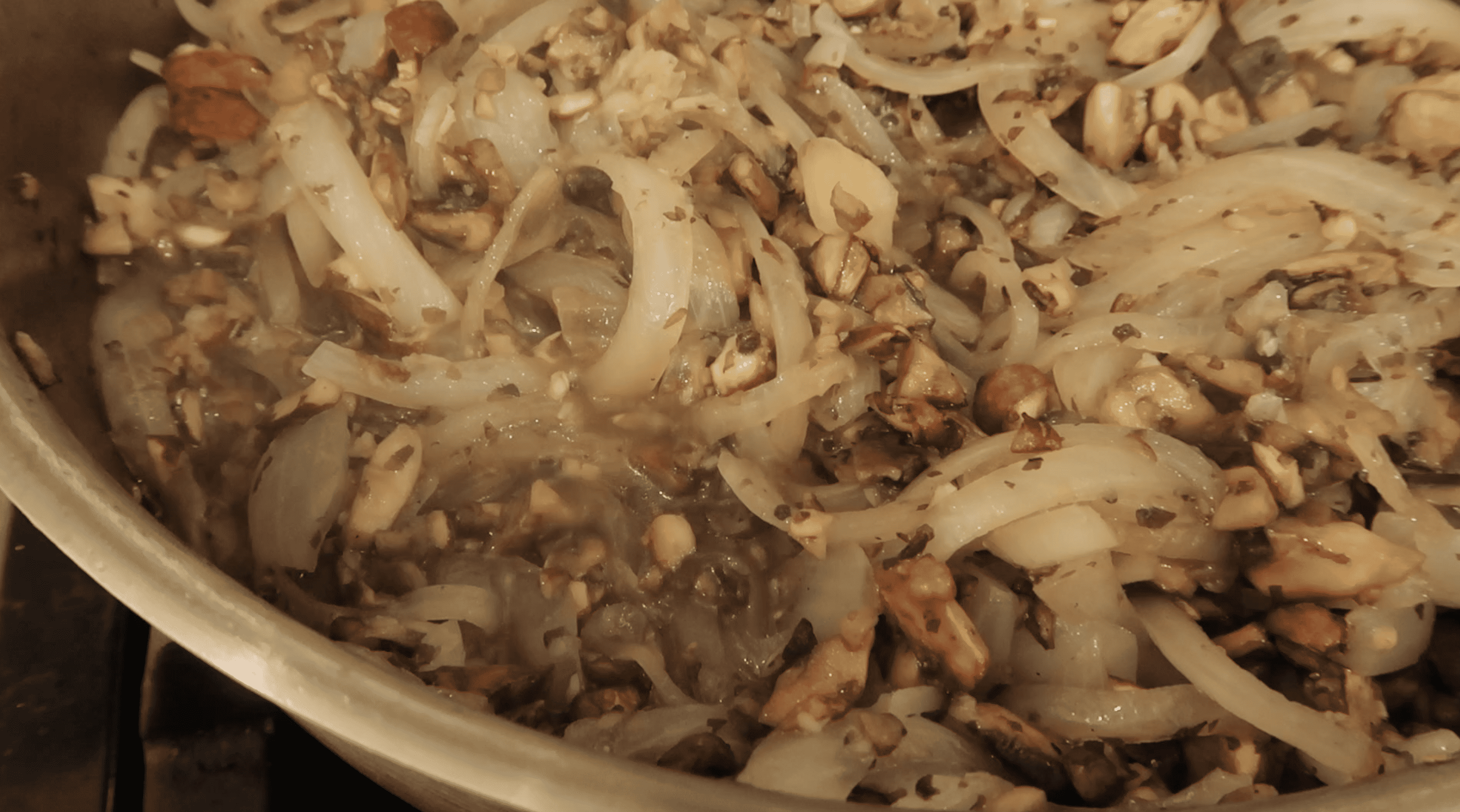a close up of onions and mushrooms cooking a pan