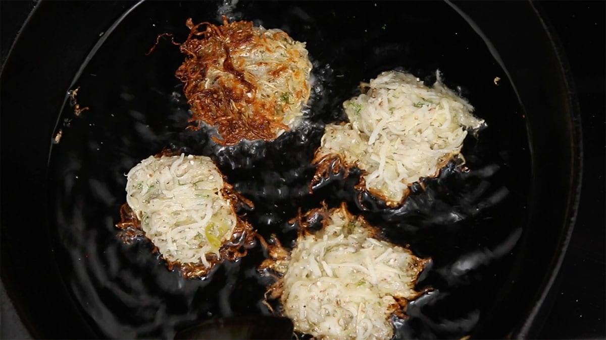 overhead of latkes frying in oil in a pan