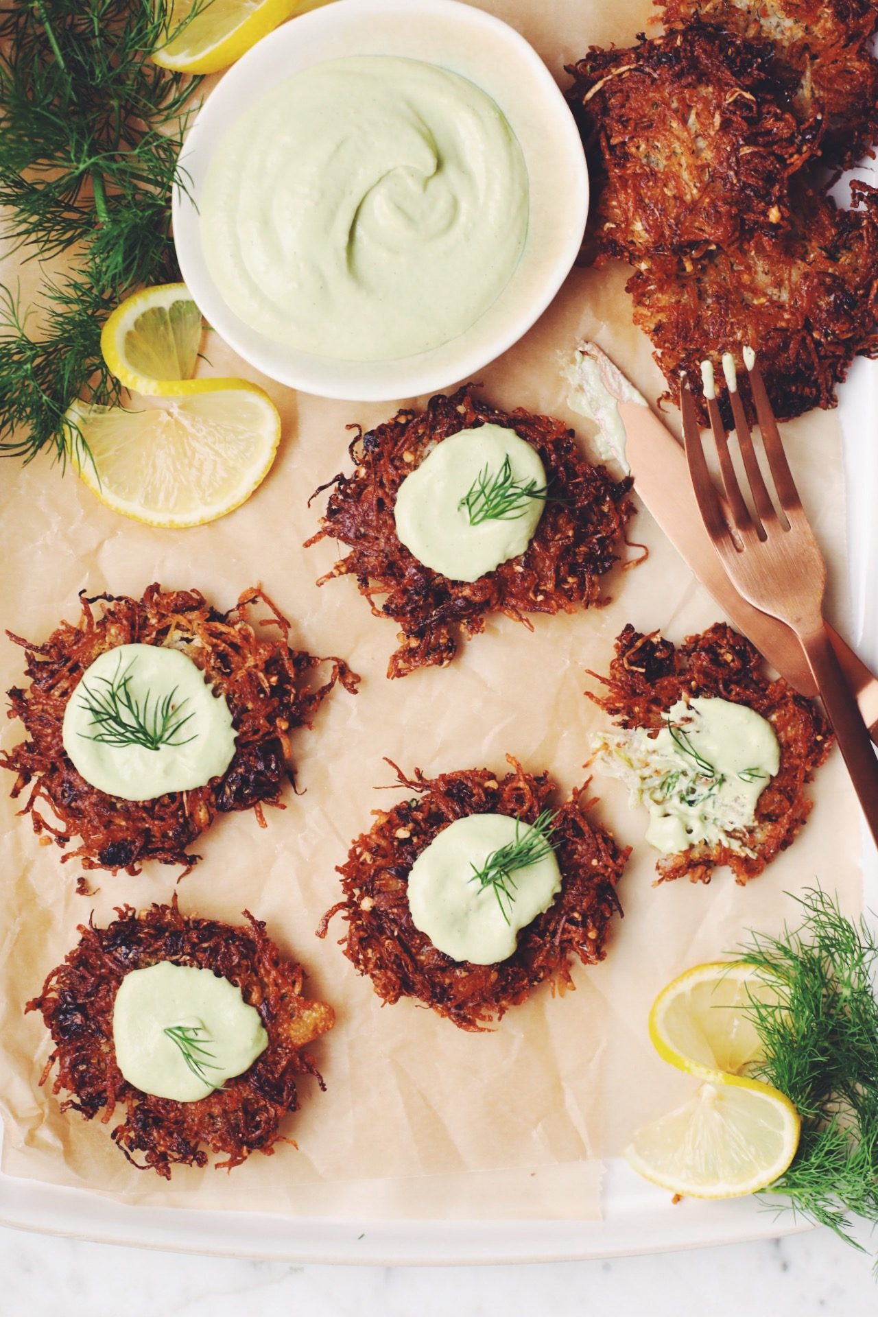overhead of a platter of vegan latkes garnished with lemon dill sour cream, and fresh dill