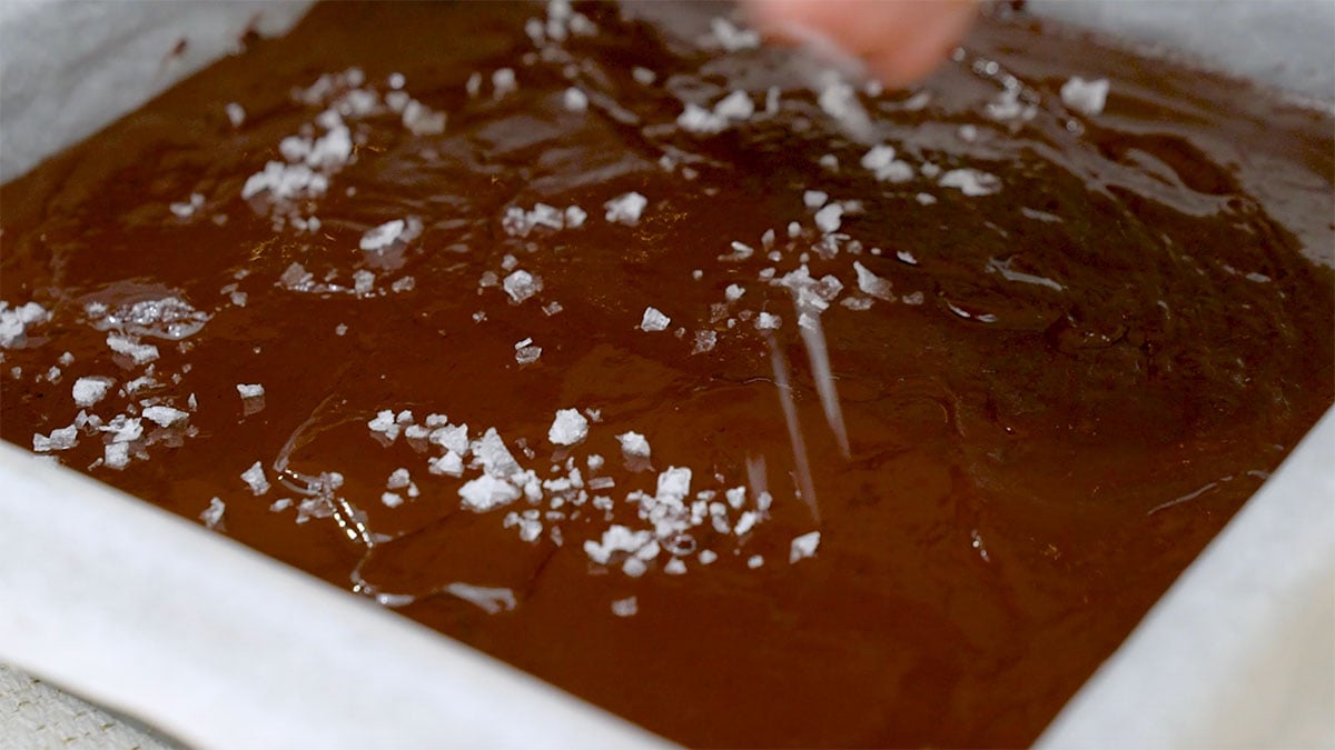 flaked salt being sprinkled onto a chocolate ganache topping