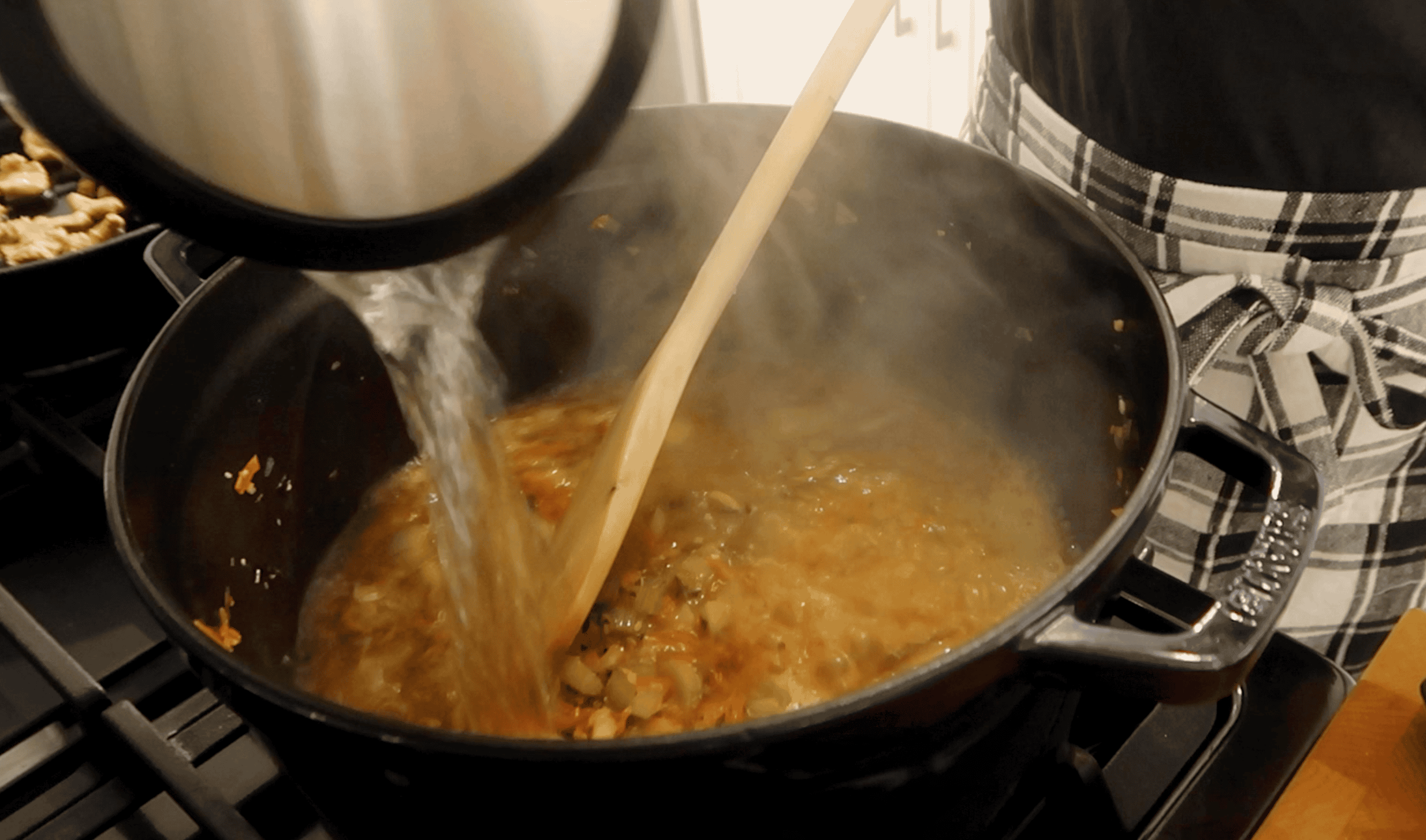 hot water being poured into a pot with soup