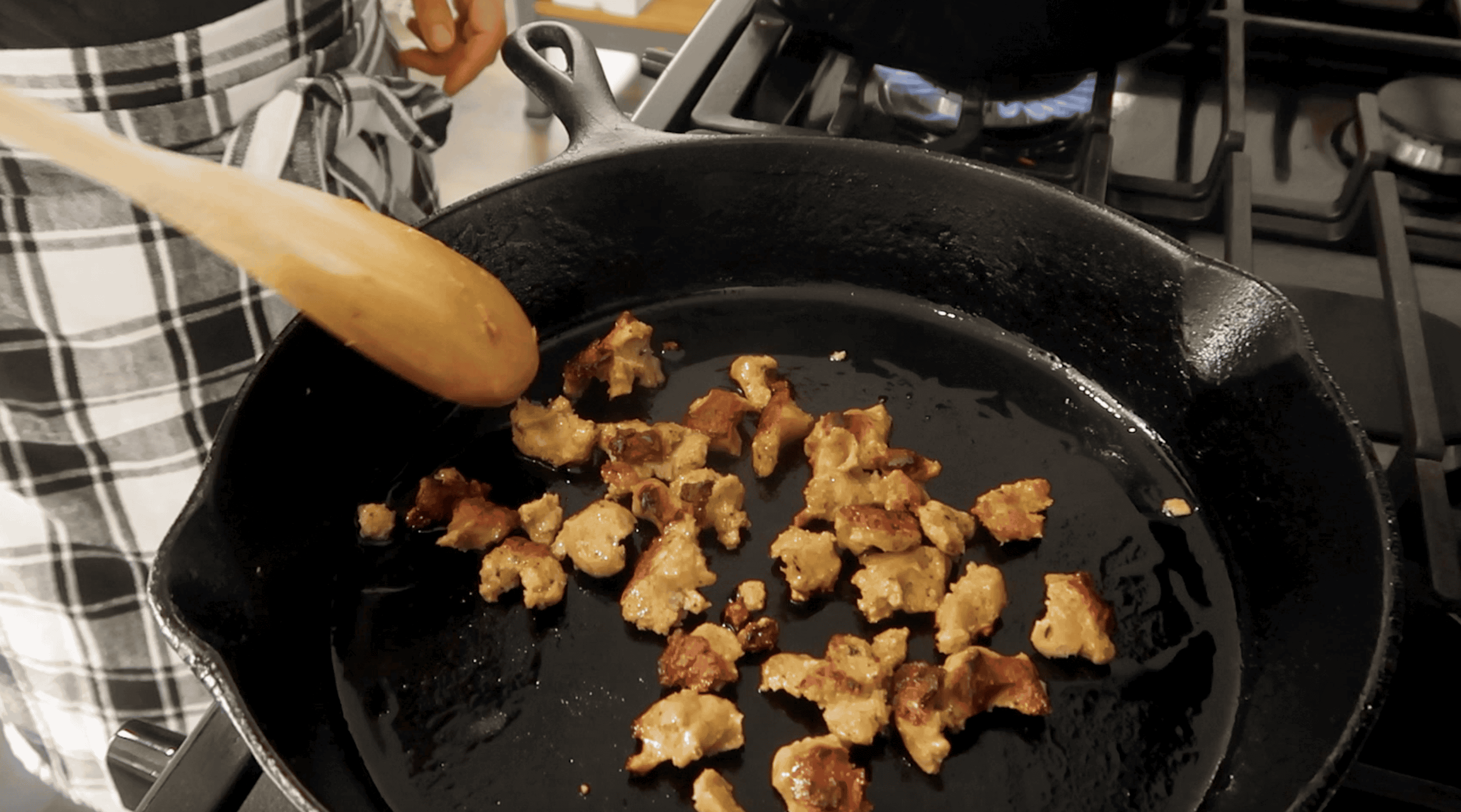 pieces of vegan sausage being browned in a cast iron pan