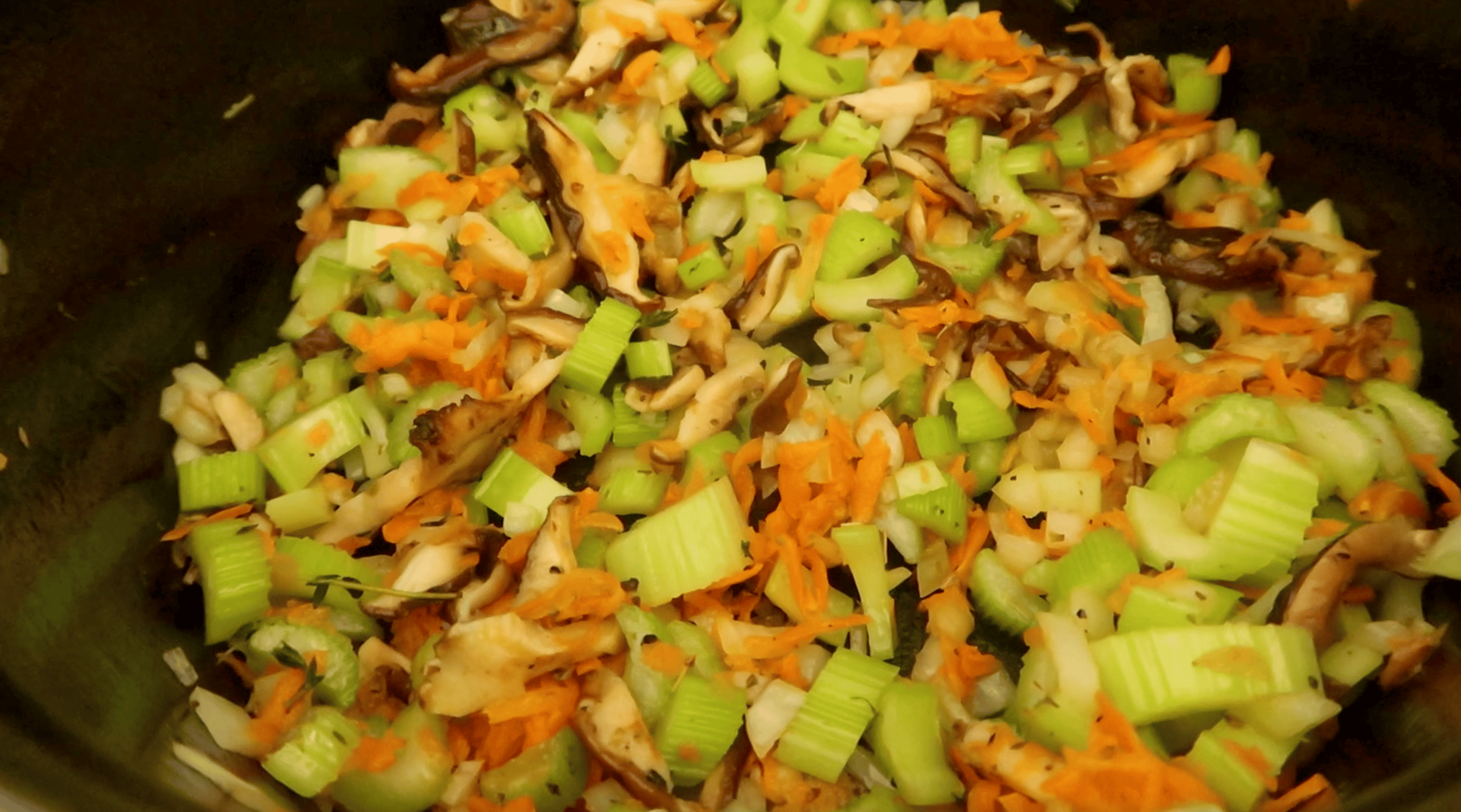 a pot with shitake, celery, onion, and carrot being cooked in it
