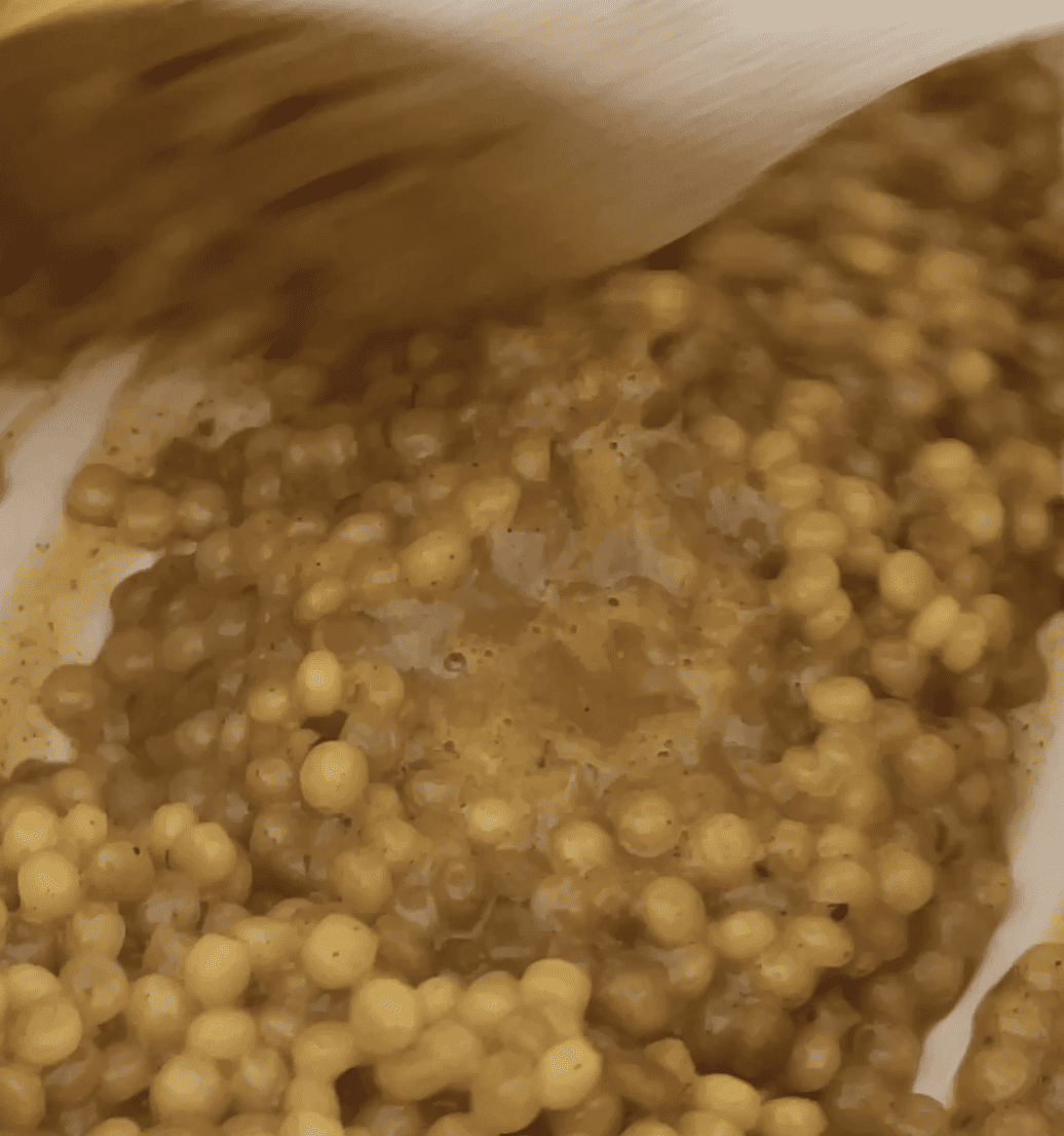 orange couscous being stirred in a pot