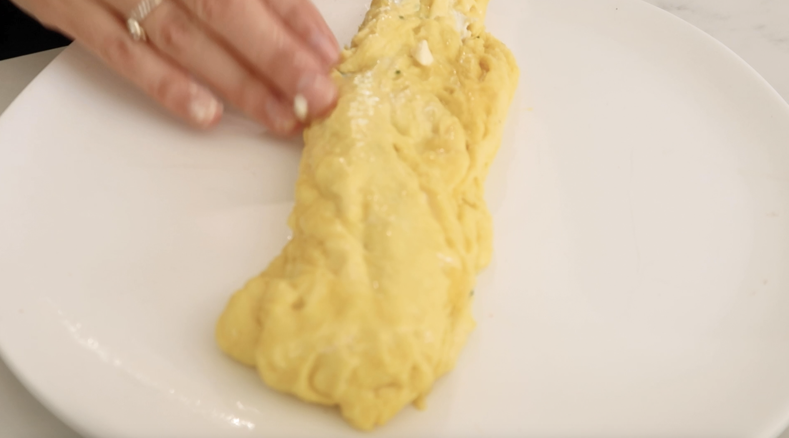 adding butter by hand to the outside of finished omelette