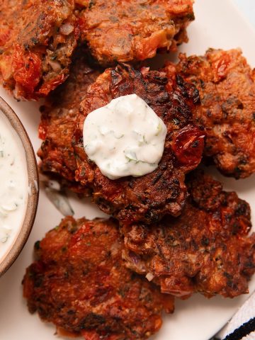 overhead of a plate of tomato fritters with yogurt dipping sauce