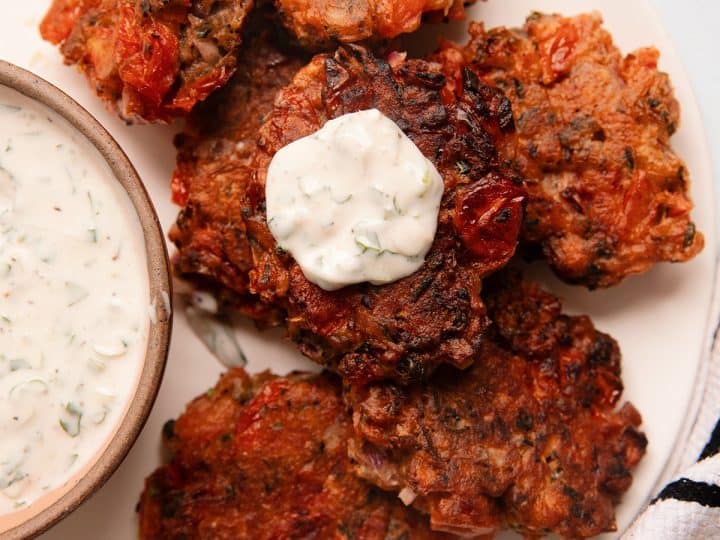 overhead of a plate of tomato fritters with yogurt dipping sauce